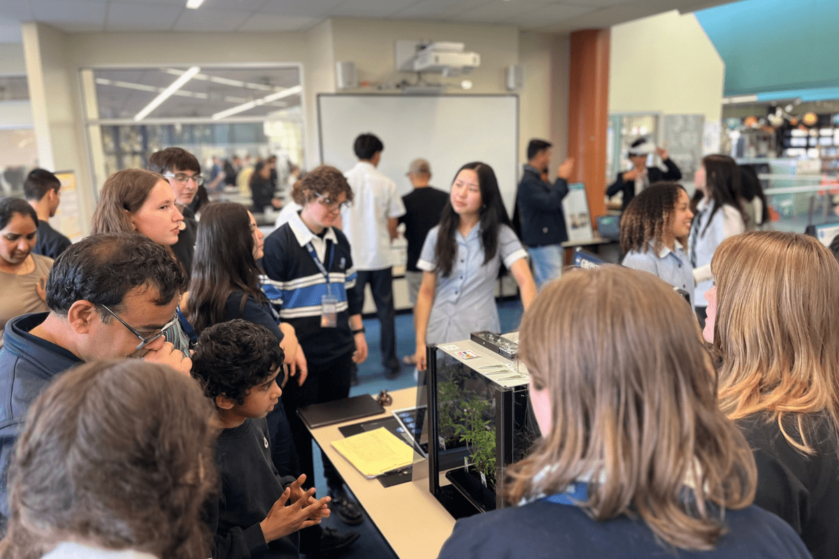 A female student showcasing a science display to a group of people