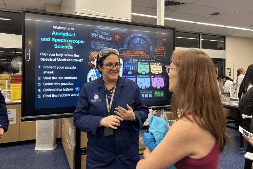 Two women chatting in front of a display screen