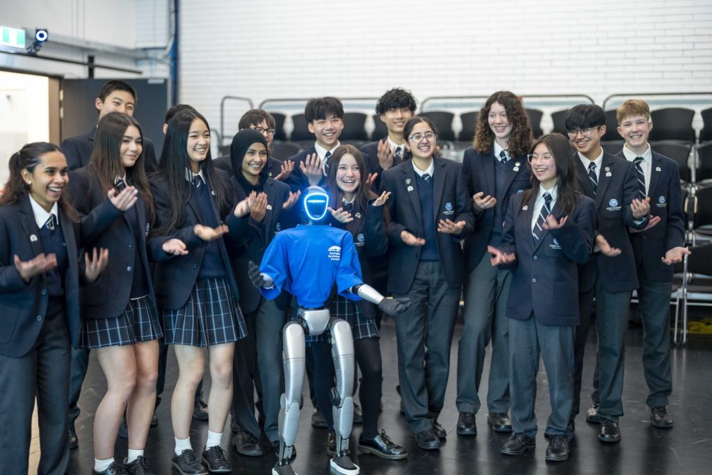 A group of students making hand gesture with a robot