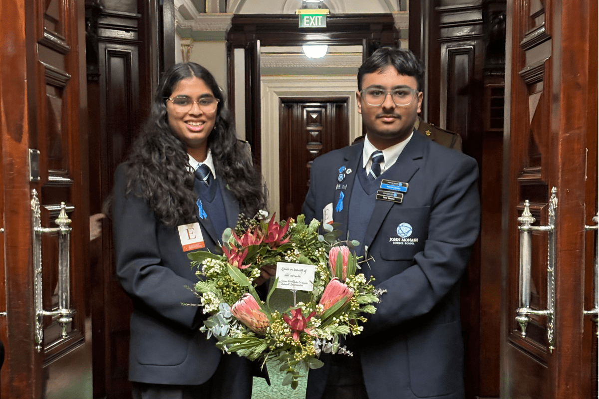 A famale and male student posting and holding a wreath