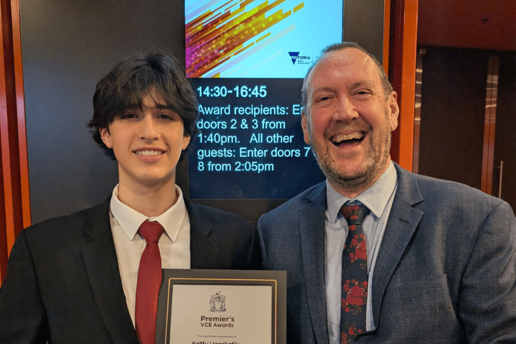 Two people posing with one holding a primer VCE award certificate