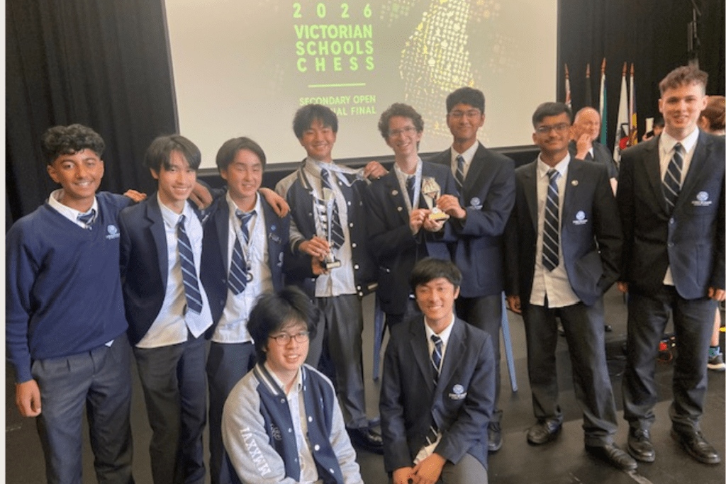 A group photo of male students, with of them holding a trophy each