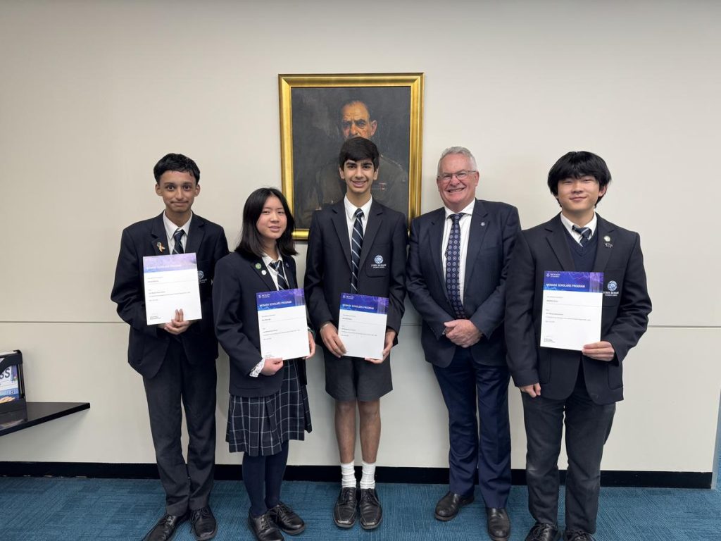 Four students each holding a certificate and posting for a picture with a school principal