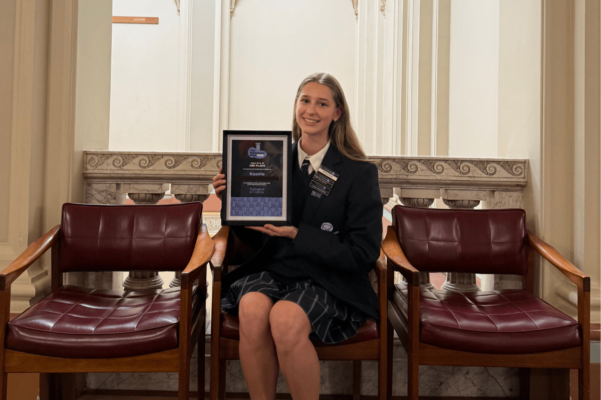 A young female student sitting and holding an award certificate